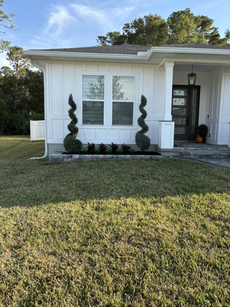 Front yard landscape installation with spiral topiary trees and fresh garden bed edging