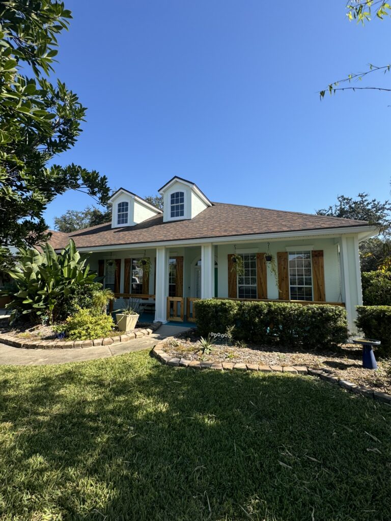 Front yard lawn with curved landscape bed and tropical foundation plantings
