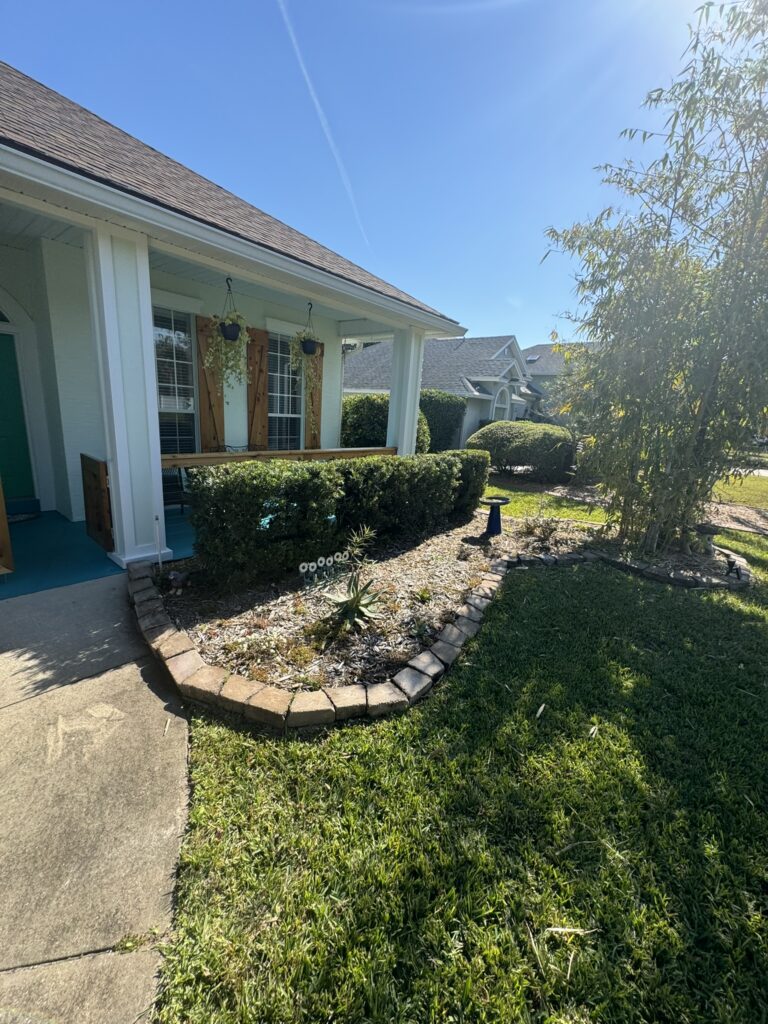 Foundation landscape bed with hedge border and stone edging along front porch